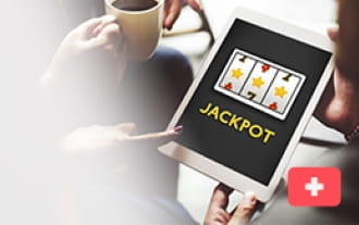 Jemand bedient ein Tablet, welches das Wort 'Jackpot' unter einem Slot zeigt.