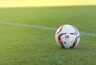 Ball mit Bundesligalogo auf Fußballplatz.