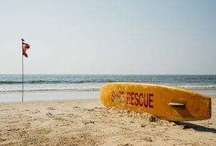 Surfbrett und Flagge an einem Strand in Goa