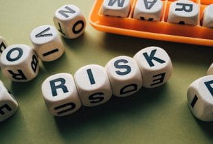 Würfel mit Buchstaben in geordneter Reihenfolge erheben das Wort „RISK“