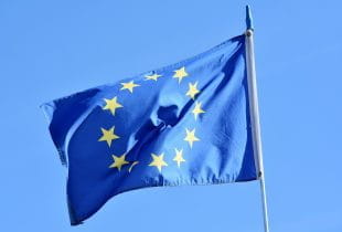 EU-Flagge im Wind vor blauem Himmel.