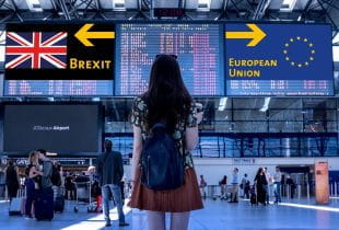 Frau am Flughafen befindet sich vor Bildschirmen mit den Kennzeichnungen Brexit und European Union.