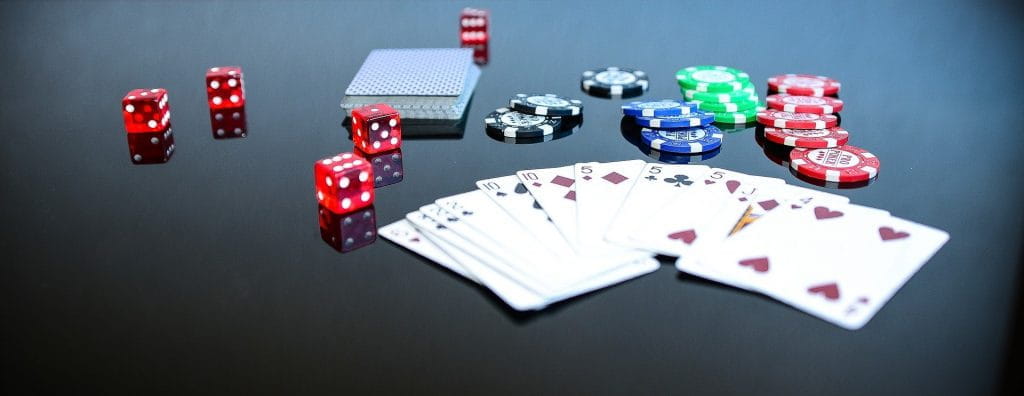 Auf einem Tisch liegen Pokerchips, Spielkarten und ein paar Würfel.