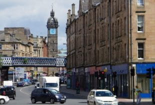 Eine Straße mit diversen Autos und Menschen in der Innenstadt von Glasgow.