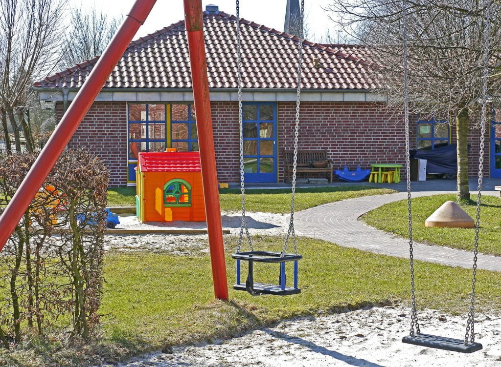 Die Terrasse inklusive Schaukel und Sandkasten eines Kindergartens.