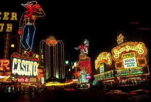 Ein Straßenabschnitt in Las Vegas mit mehreren Casinos bei Nacht.