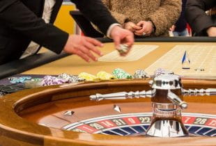 An einem Roulette-Tisch platzieren verschiedene Spieler ihre Jetons.