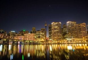 Hell beleuchtete Skyline der Stadt Sydney in Australien bei Nacht.