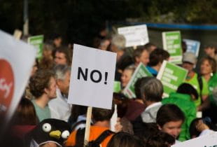 Protestbewegung mit einem No-Schild im Vordergrund.