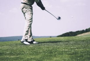 Ein Golfer schlägt mit einem Eisen einen Golfball.