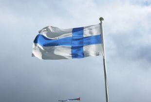 Die Flagge Finnlands weht an einem Mast im Wind.